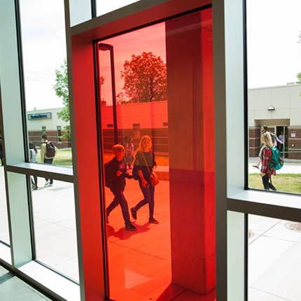 Two students walking behind a red pane of glass at Spokane Falls Community College
