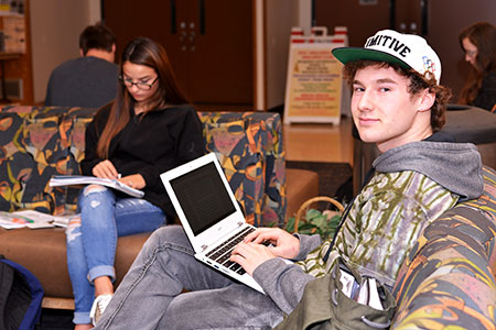 Student using a laptop in the student union building lounge.